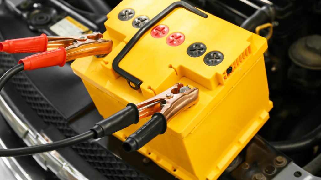 Bateria automotiva auxiliar enviando carga para a bateria de um carro.